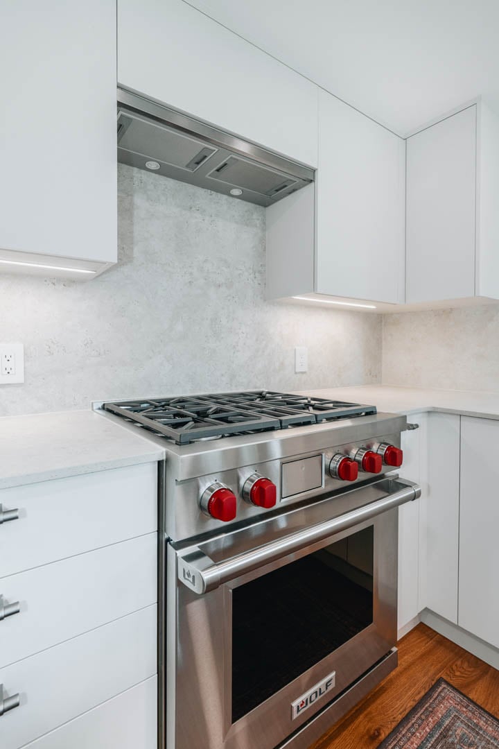 55-00-Premium Wolf gas range with iconic red knobs in a clean white custom kitchen, Vancouver.