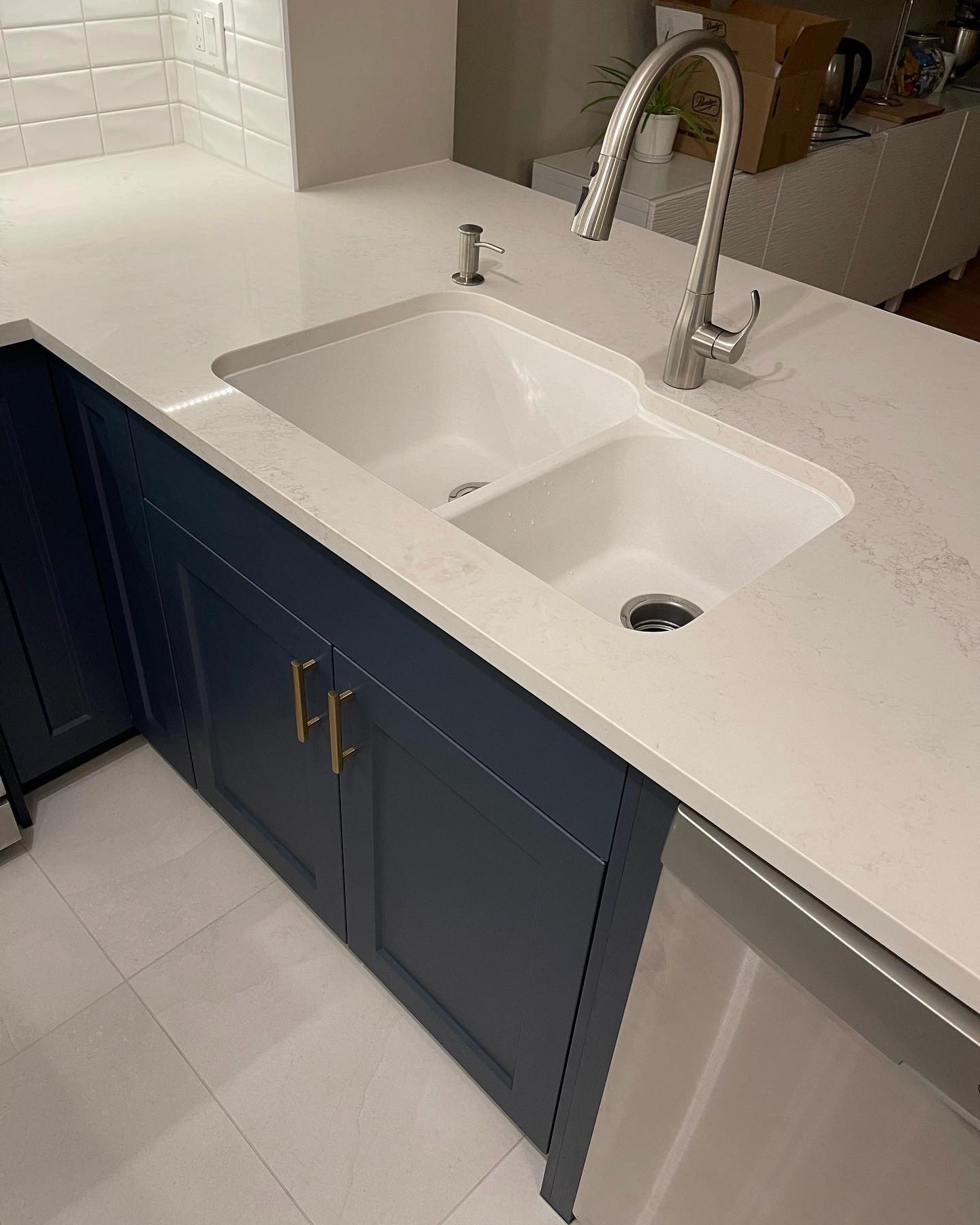 09-00-Close-up of a double sink in a quartz countertop over dark blue cabinets in a Vancouver kitchen.