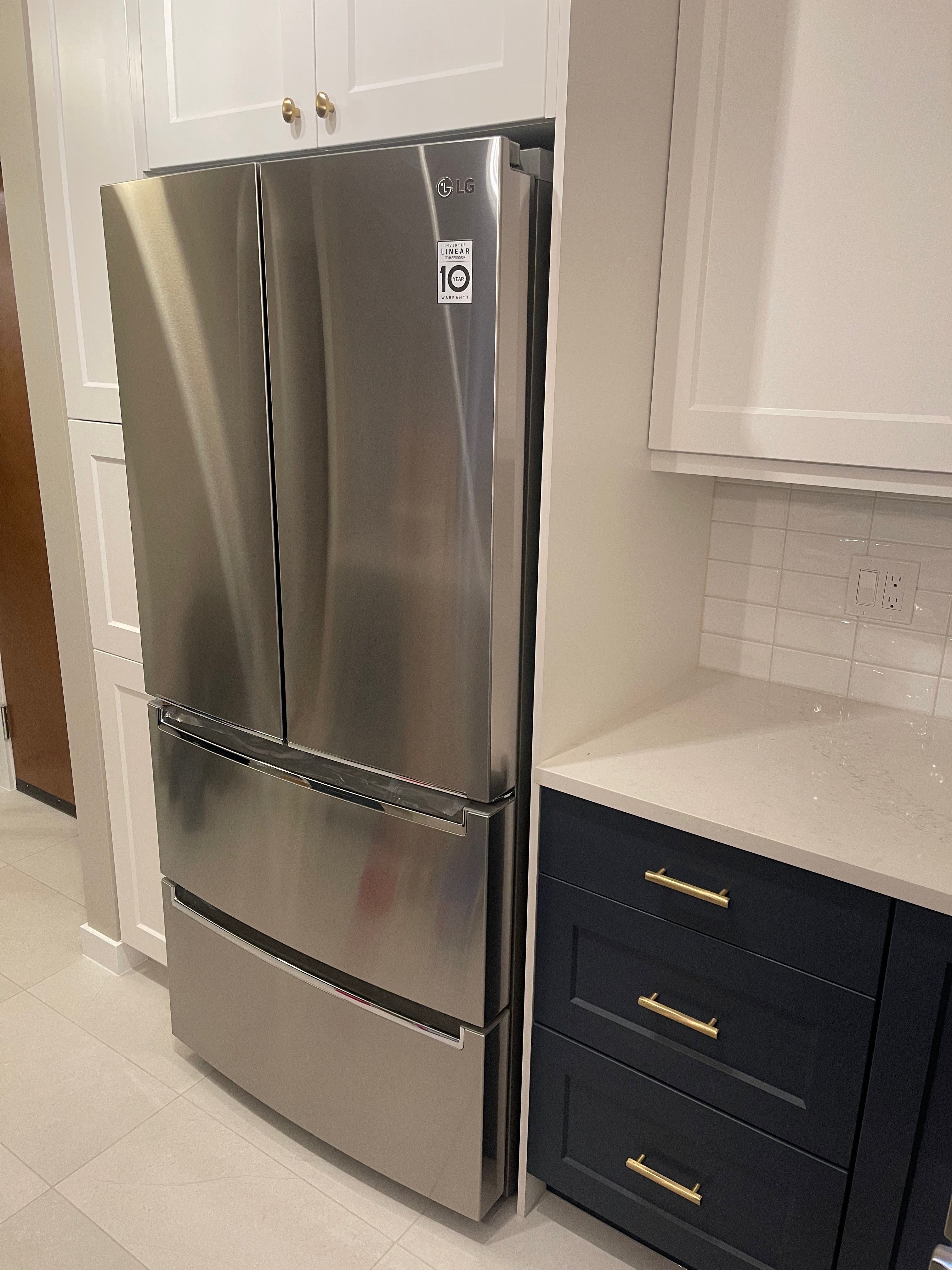 09-00-Stainless steel French door refrigerator and white cabinets with navy drawers in a Vancouver kitchen