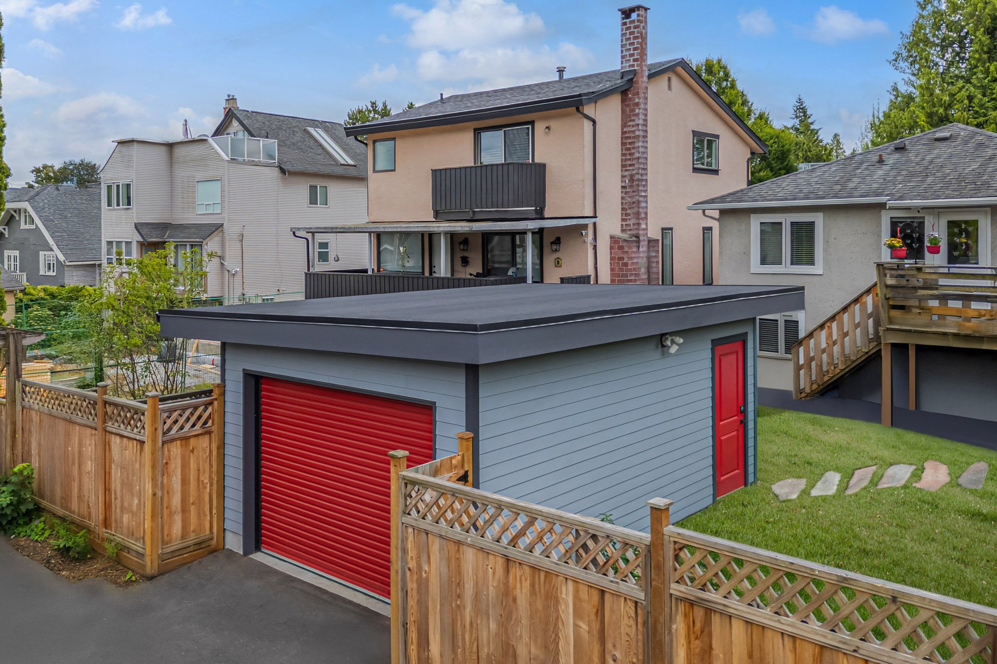 Elevated aerial view of a detached grey garage with a red roll-up door and flat roof, located in a residential neighborhood.